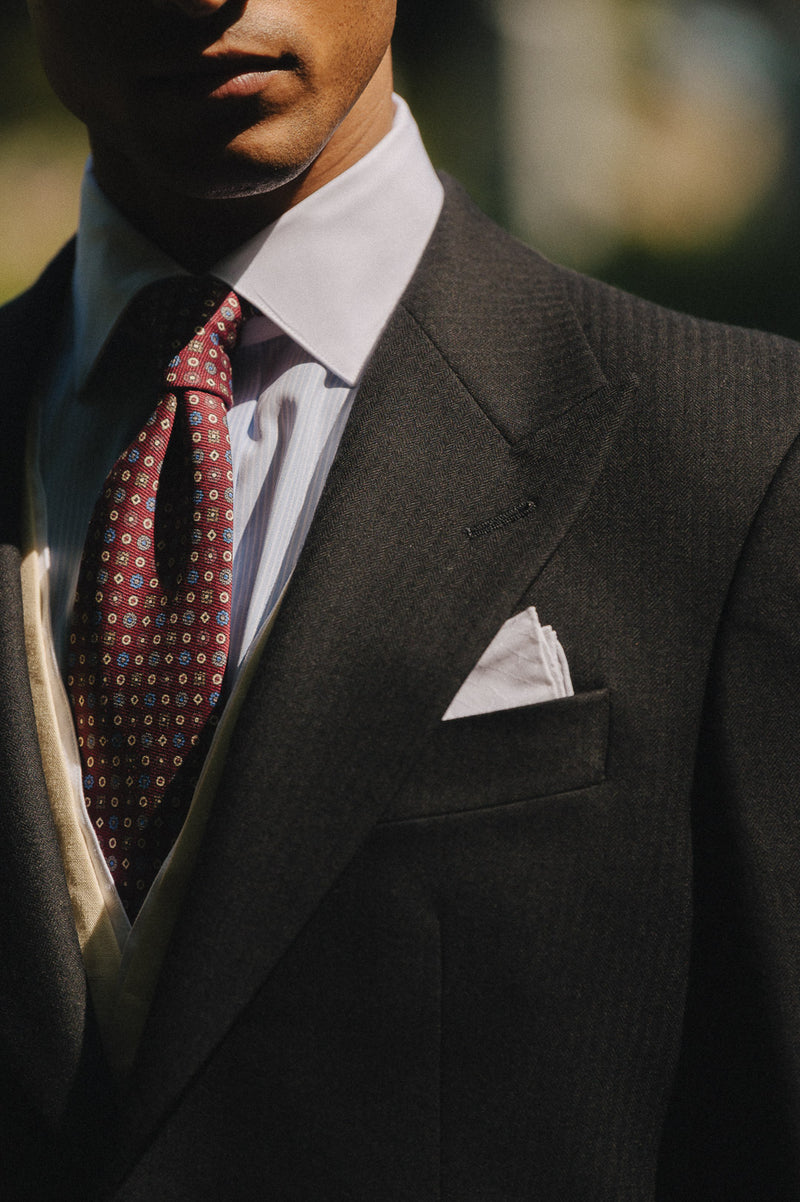 Man wearing a dark suit with a patterned tie and pocket square.