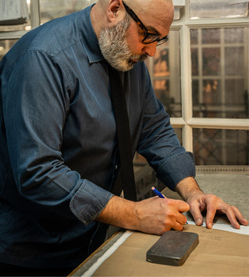 Bespoke cutter Darren Tieran in the cutting room drawing a shirt pattern
