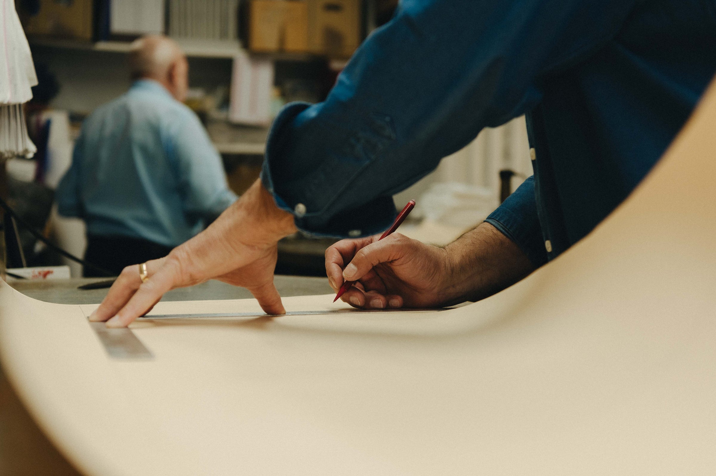 Bespoke shirt cutters drawing out patterns in cutting room