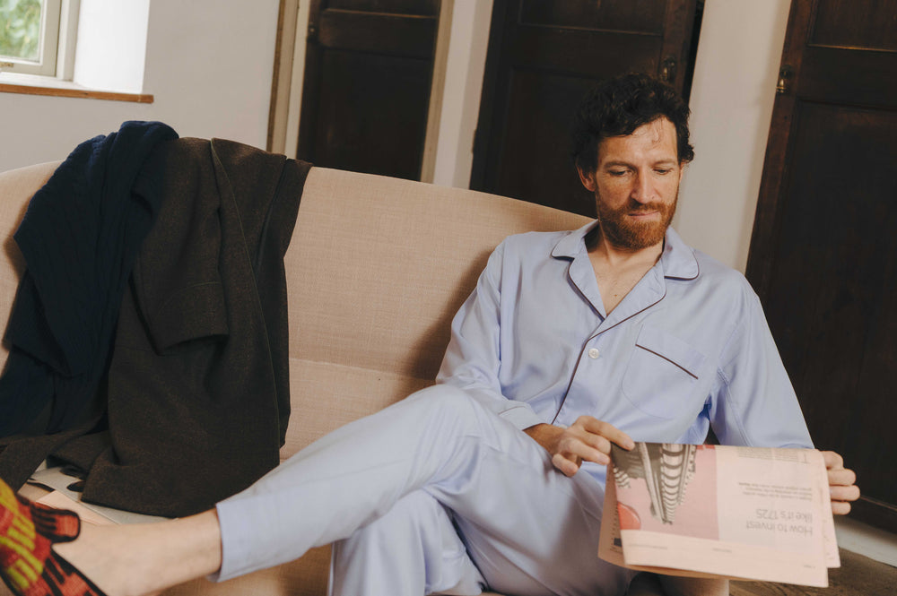 Man sat reading newspaper wearing  blue pyjamas