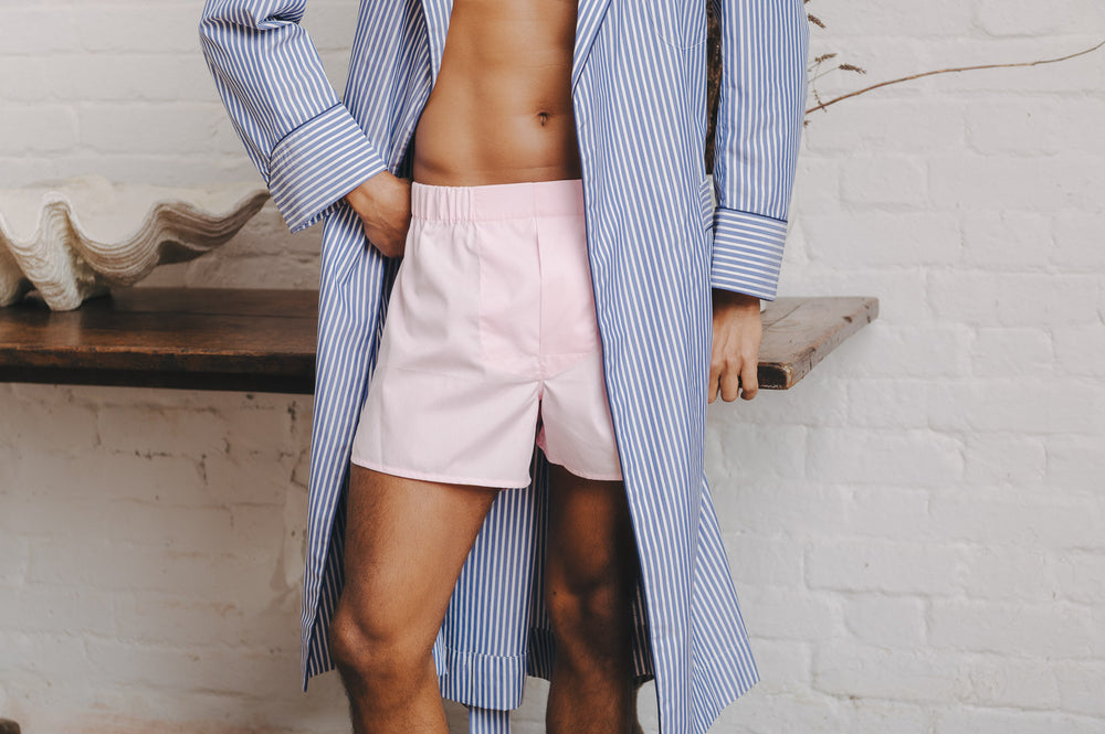 Person wearing light pink boxer shorts and a blue striped gown in a casual setting.