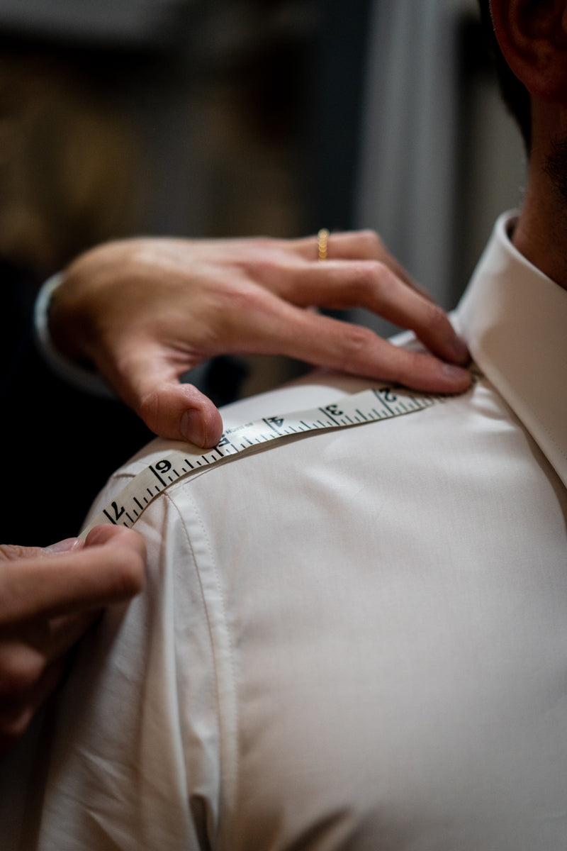 Man in white shirt being measured for shoulder measurements