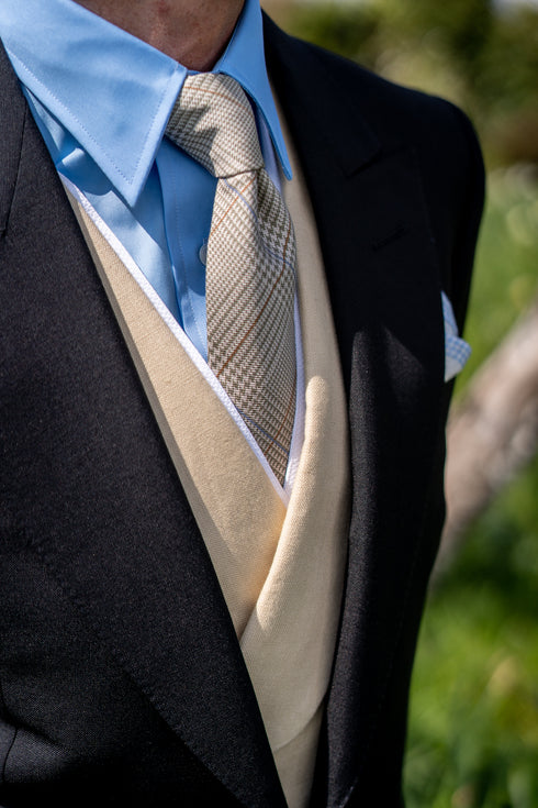 Close up detail of man wearing a checked tie and peach colour waistcoat with a morning suit for a wedding
