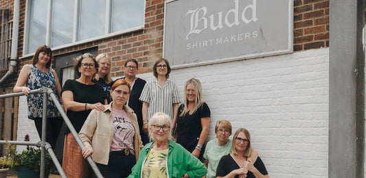 Andover workroom team posing in front of a building with 'Budd Shirtmakers' sign.