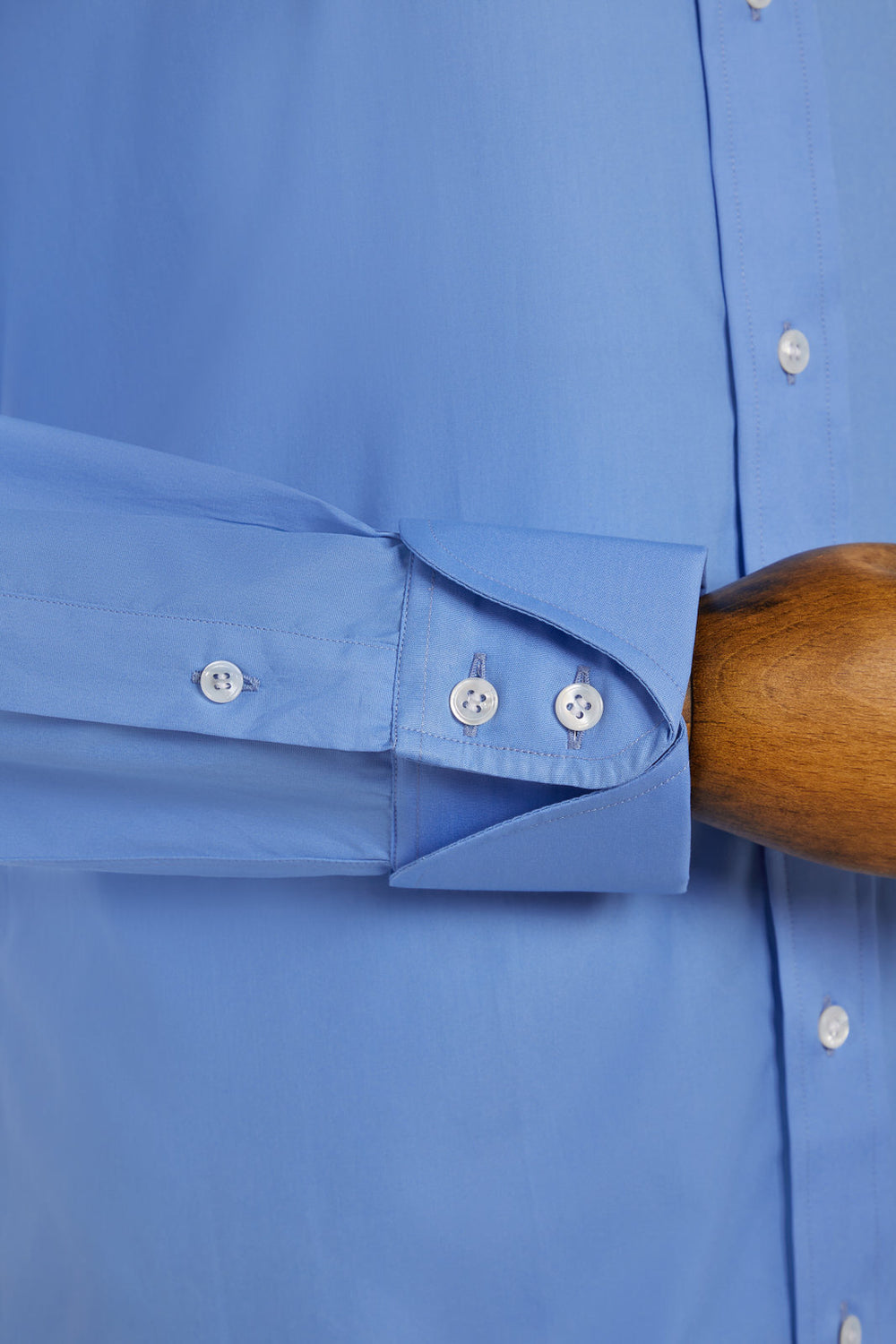 Close-up of a blue shirt with rolled-up sleeve and wooden handle.
