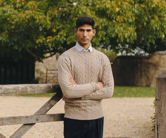 Male model wearing beige cable knit crew neck jumper in the garden