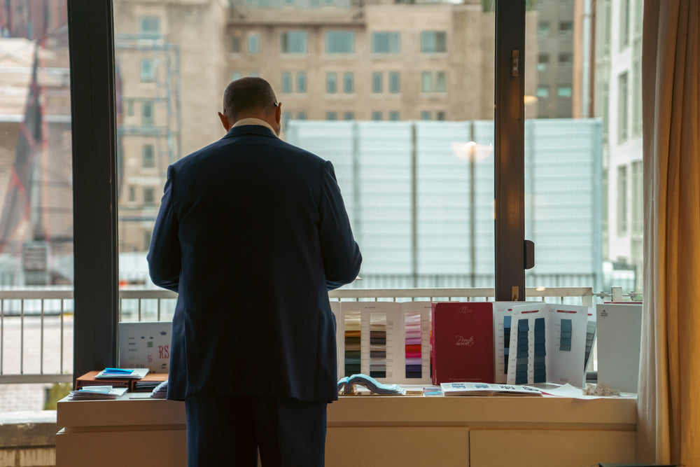 Shirt cutter stood at sideboard with shirt swatches