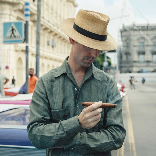 Kirby Allison in Havana street wearing a khaki green linen shirt holding a cigar