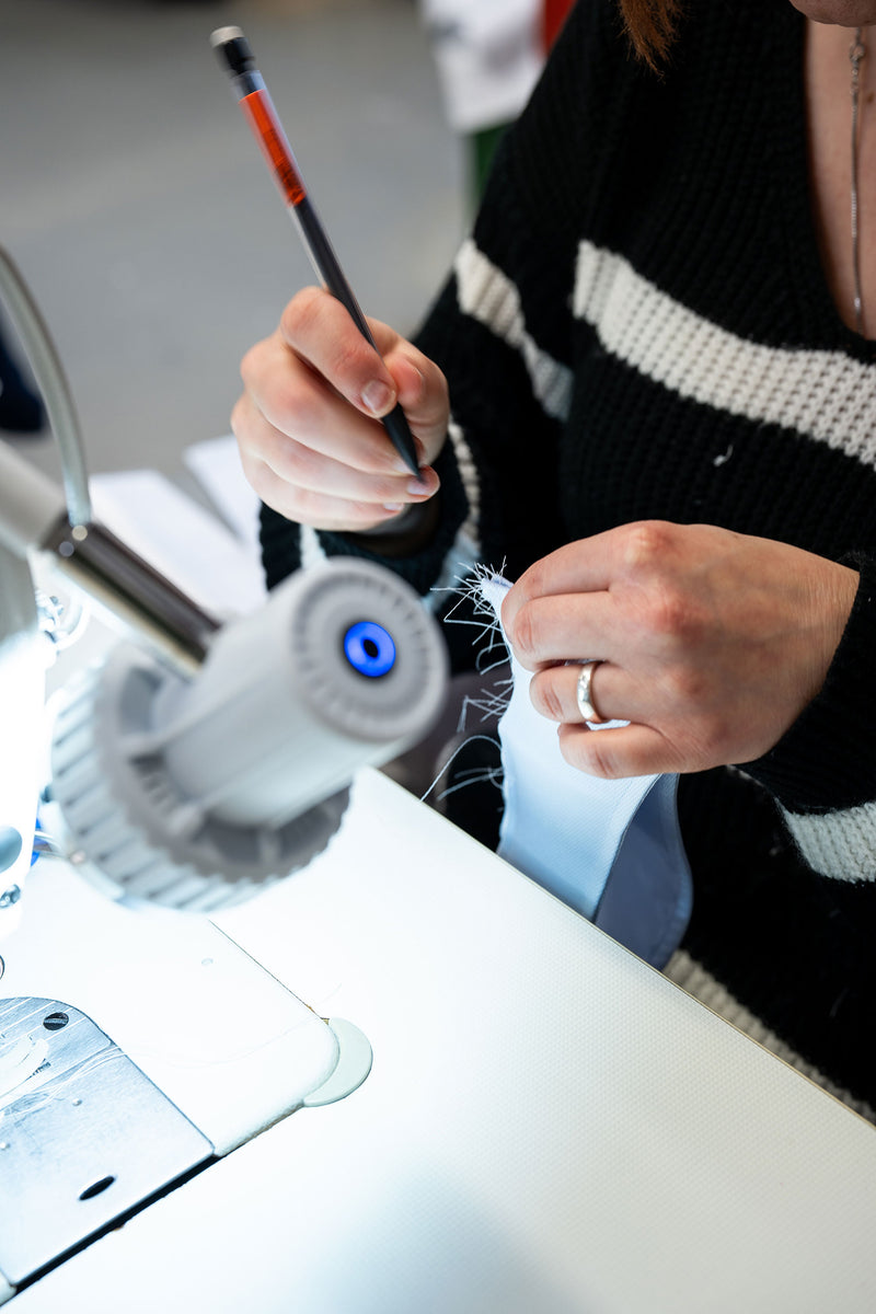Person using a sewing machine with a close-up of hands and equipment.
