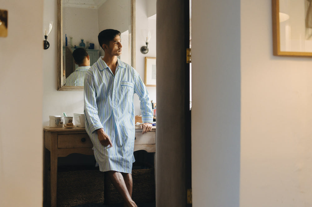 Man in a striped nightshirt standing in a bedroom