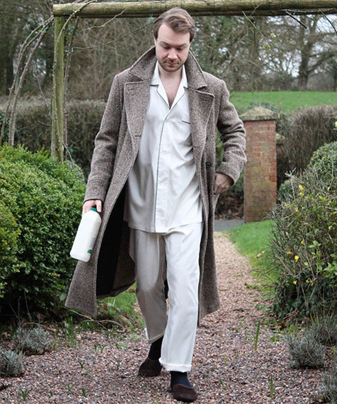 Man walking up garden path in pyjamas and dressing gown with a pint of milk in hand