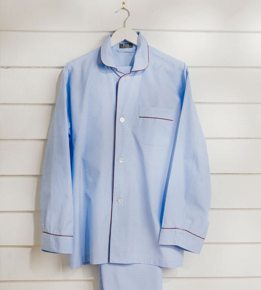 Blue pyjama set hung on hanger against white wall