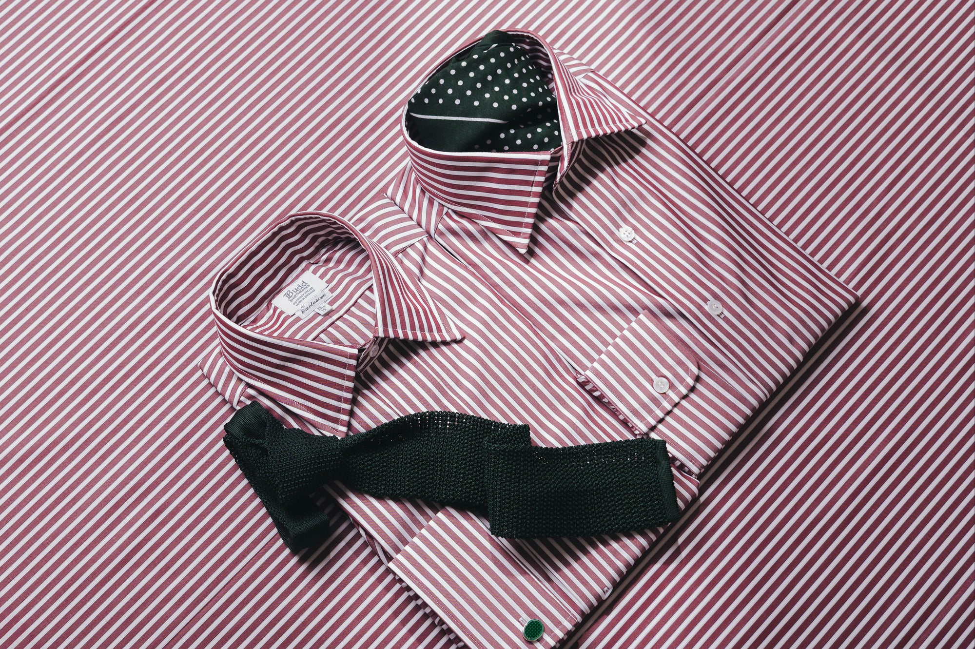 Burgundy stripe shirts laid out on matching fabric background
