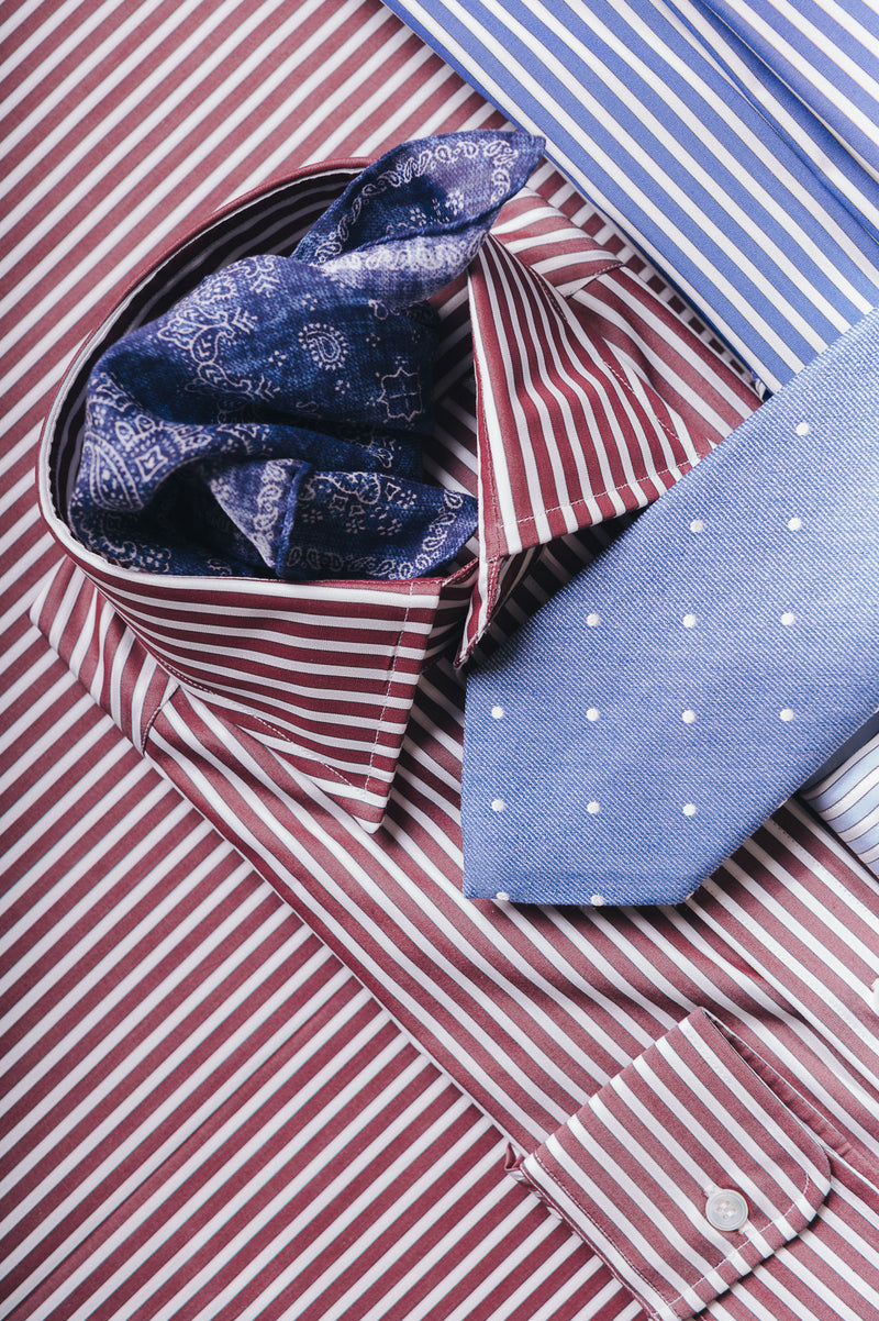 Burgundy stripe shirts laid out on matching fabric background