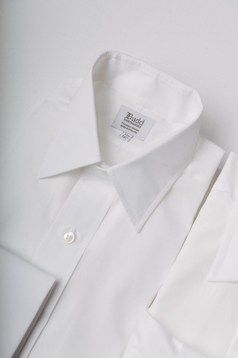 Close-up of a white shirt with a collar and label on a light gray background