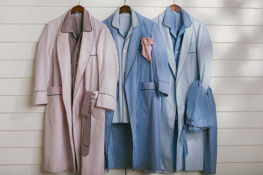 Close up of three stripe dressing gowns hung up against white wooden wall