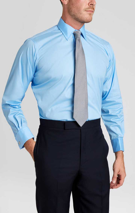 Man wearing blue shirt and tie with suit trousers against plain cream background