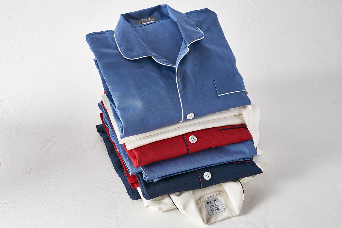 Stack of folded pajama sets in blue, red, and navy on a white background